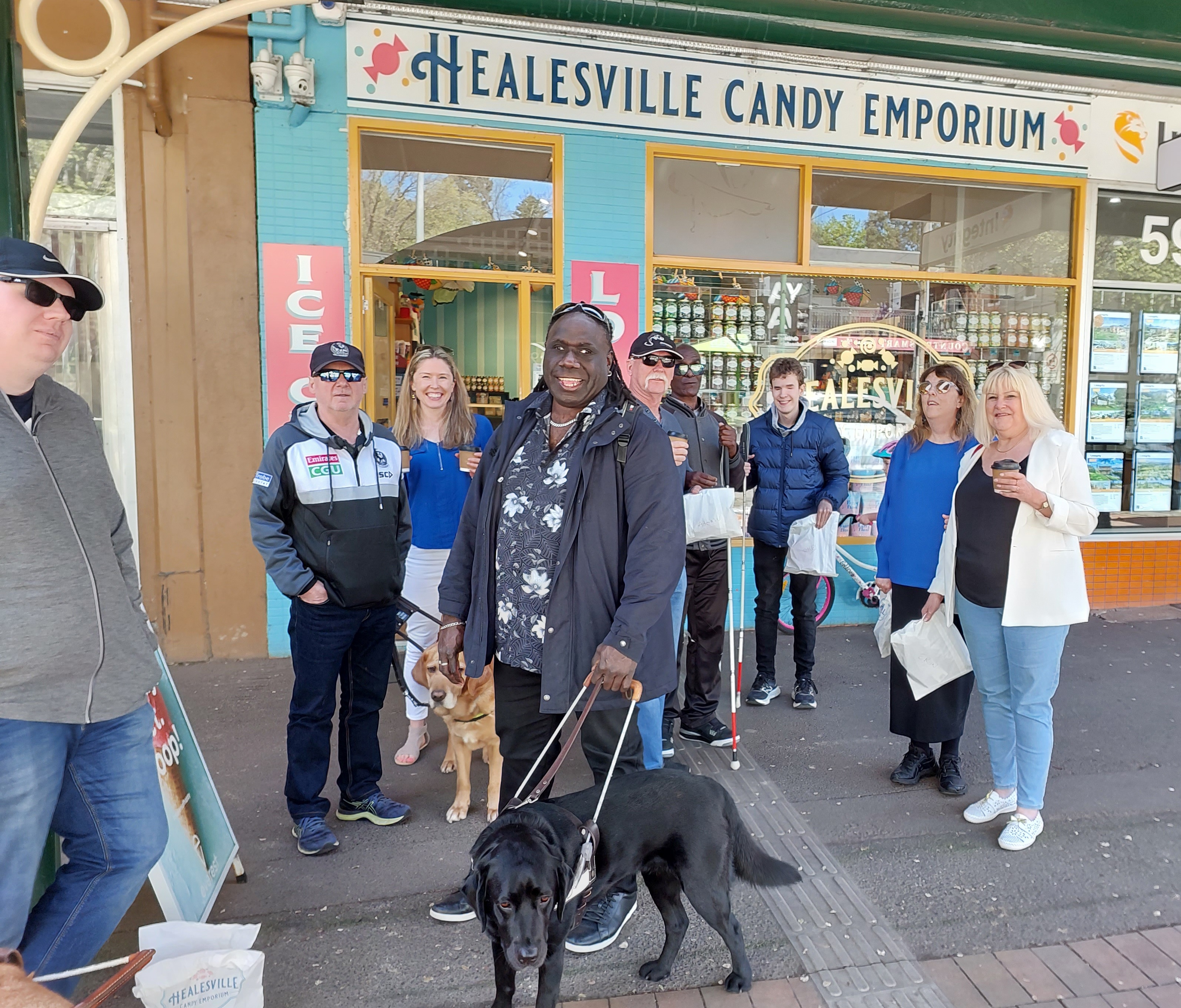 group photo outside healesville candy shop with man and guide dog in front
